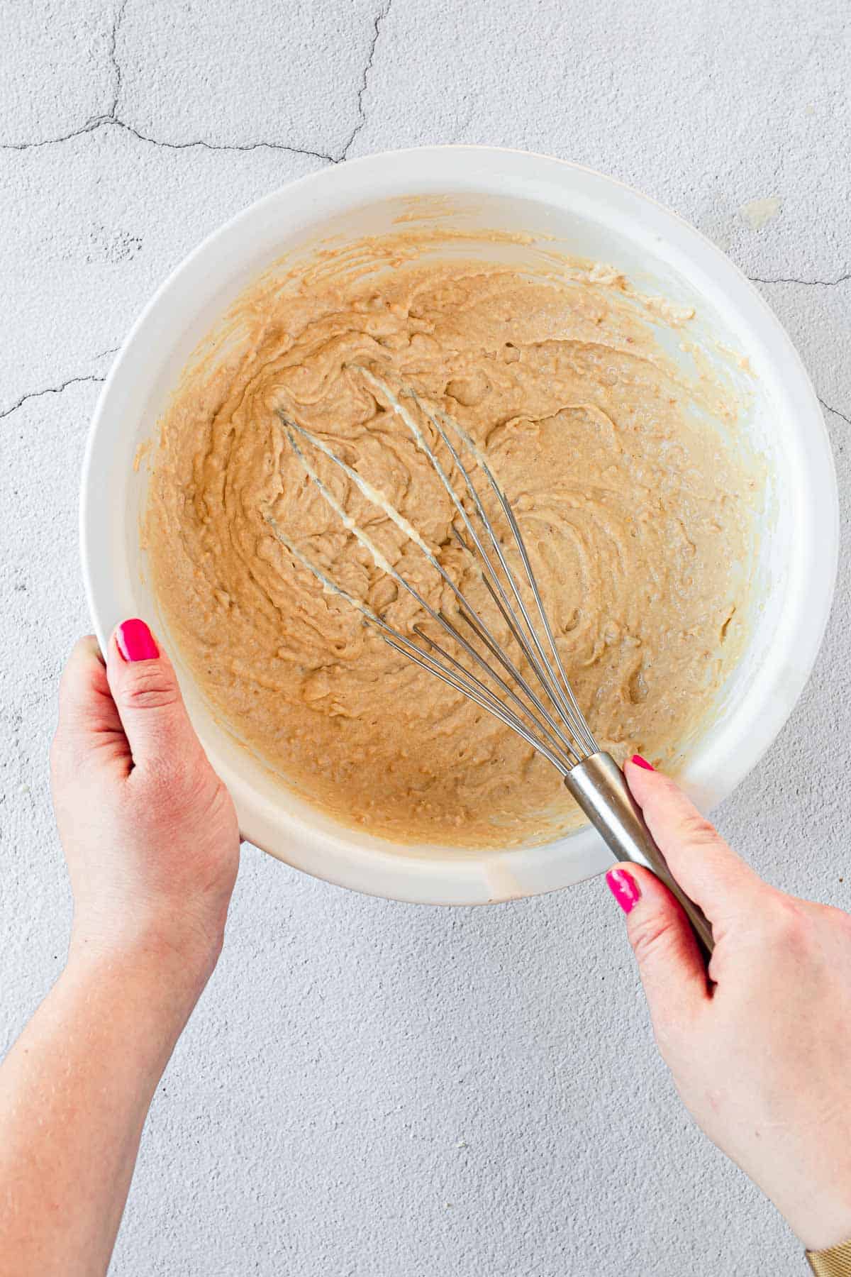 A person whisking batter for gluten free blueberry chocolate chip muffins.