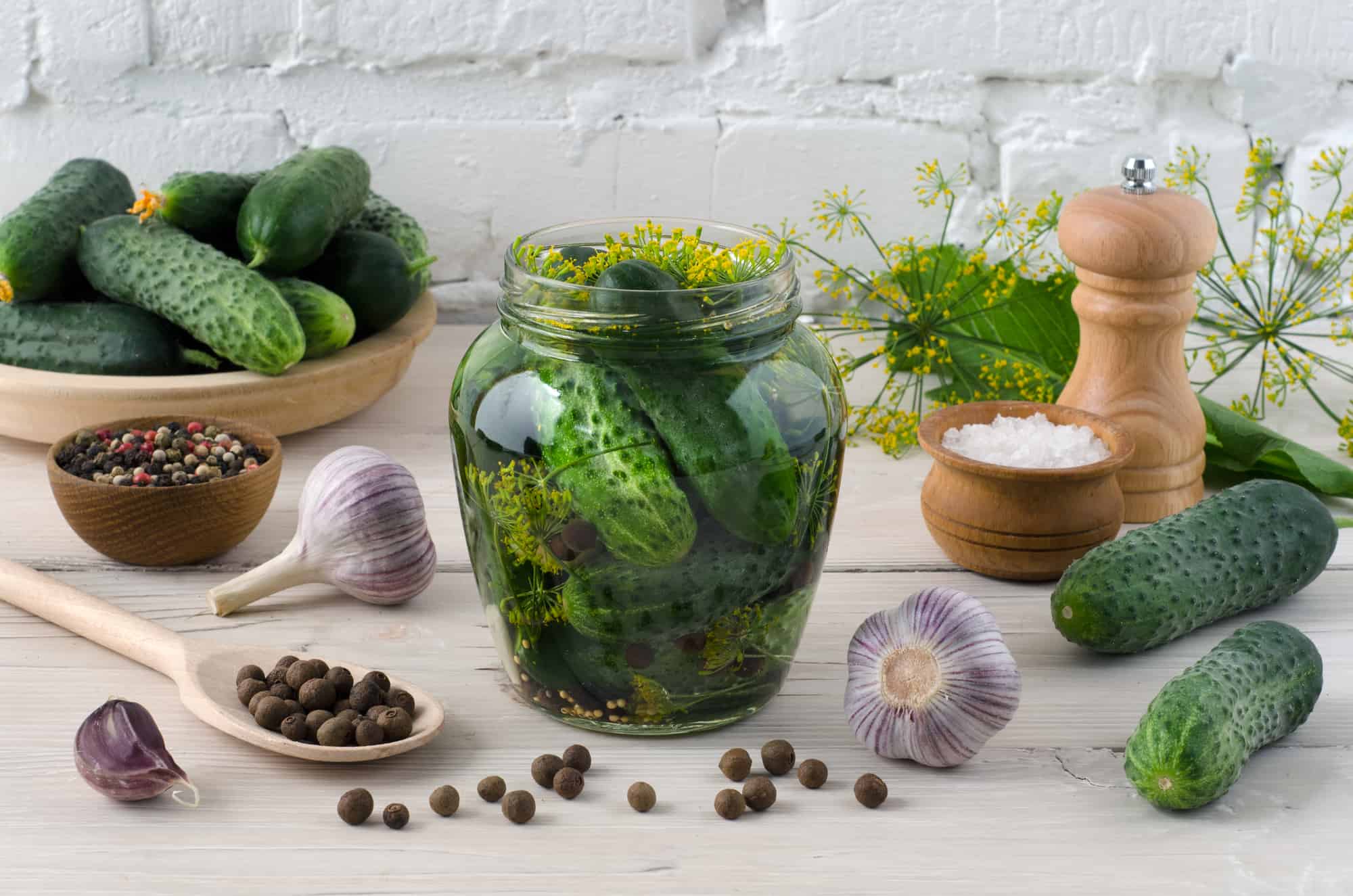 A jar of fermented pickles on a wooden table.