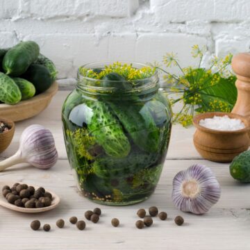 Description: Fermented pickles in a jar on a wooden table.
