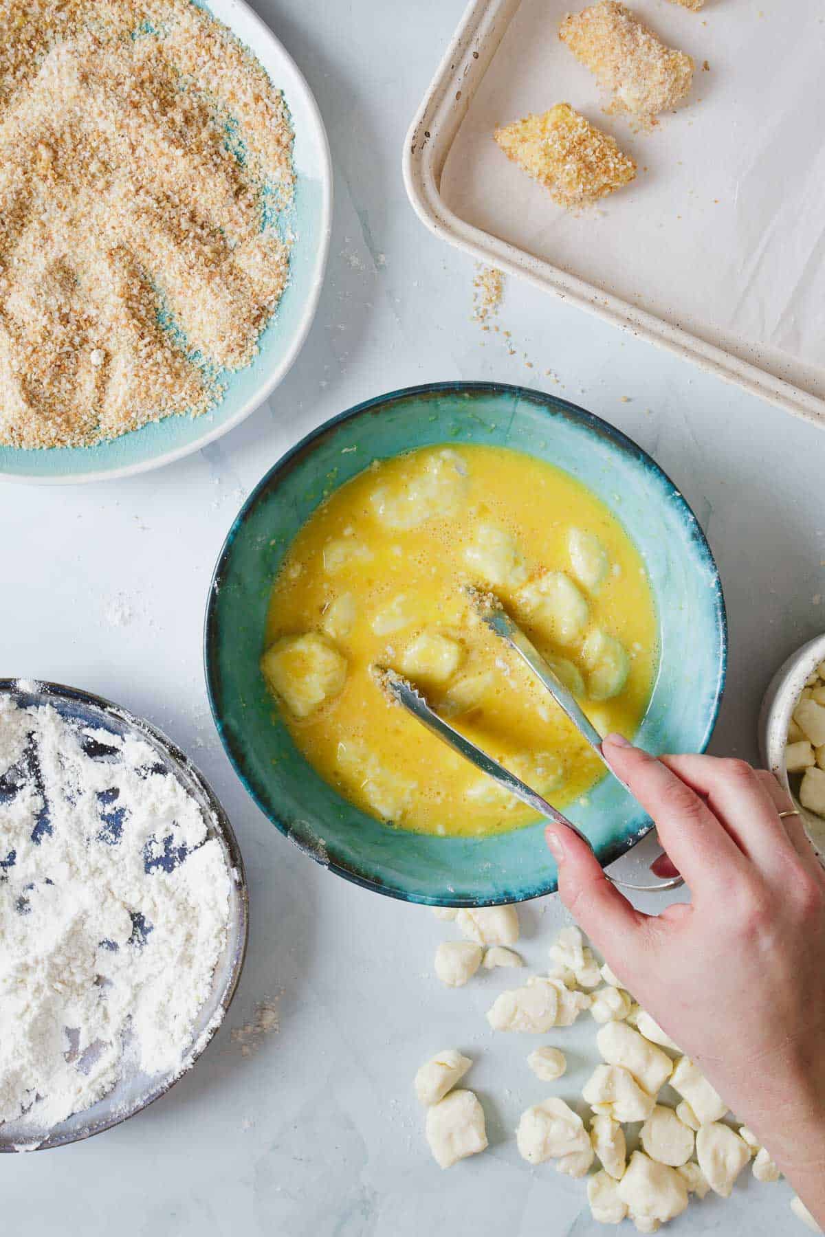 A person is mixing cheese curds in a bowl of eggs.