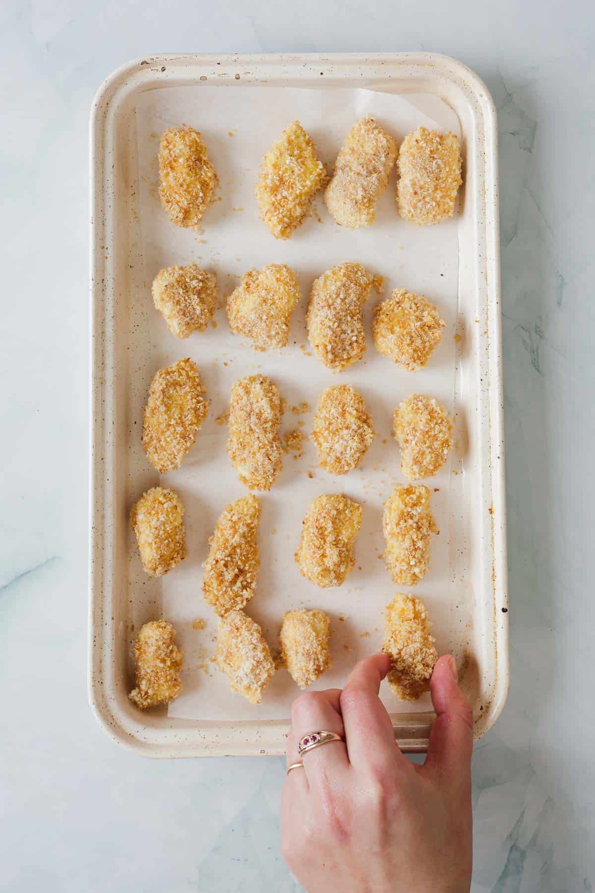 coated cheese curds are on a pan.