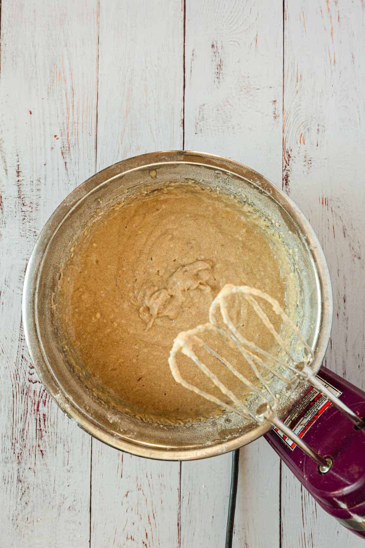 A bowl of batter with a whisk in it.