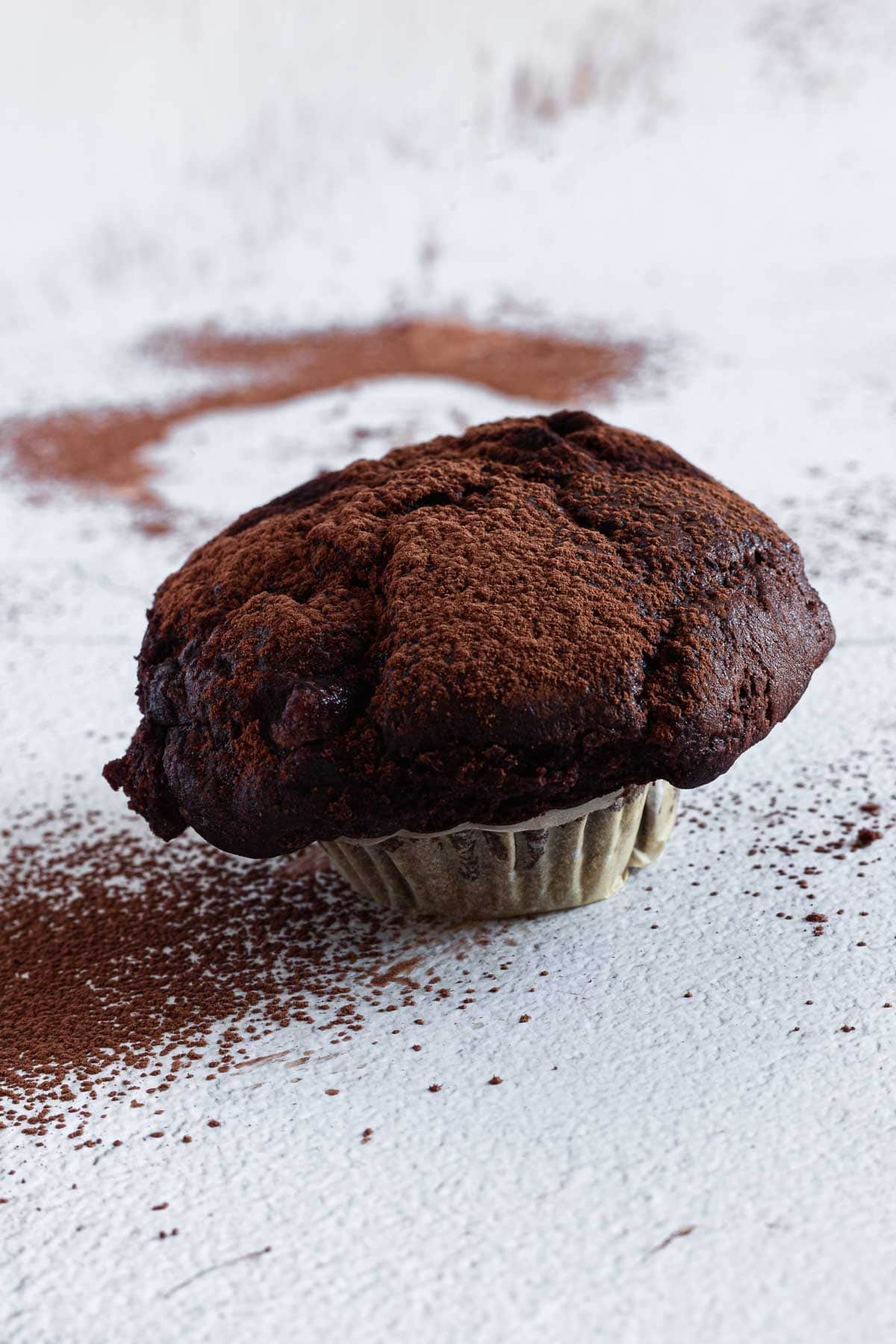 A chocolate cupcake sitting on a white surface.