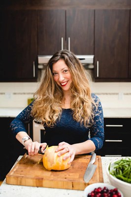 A woman cutting a pumpkin in a kitchen while preparing healthy international recipes.