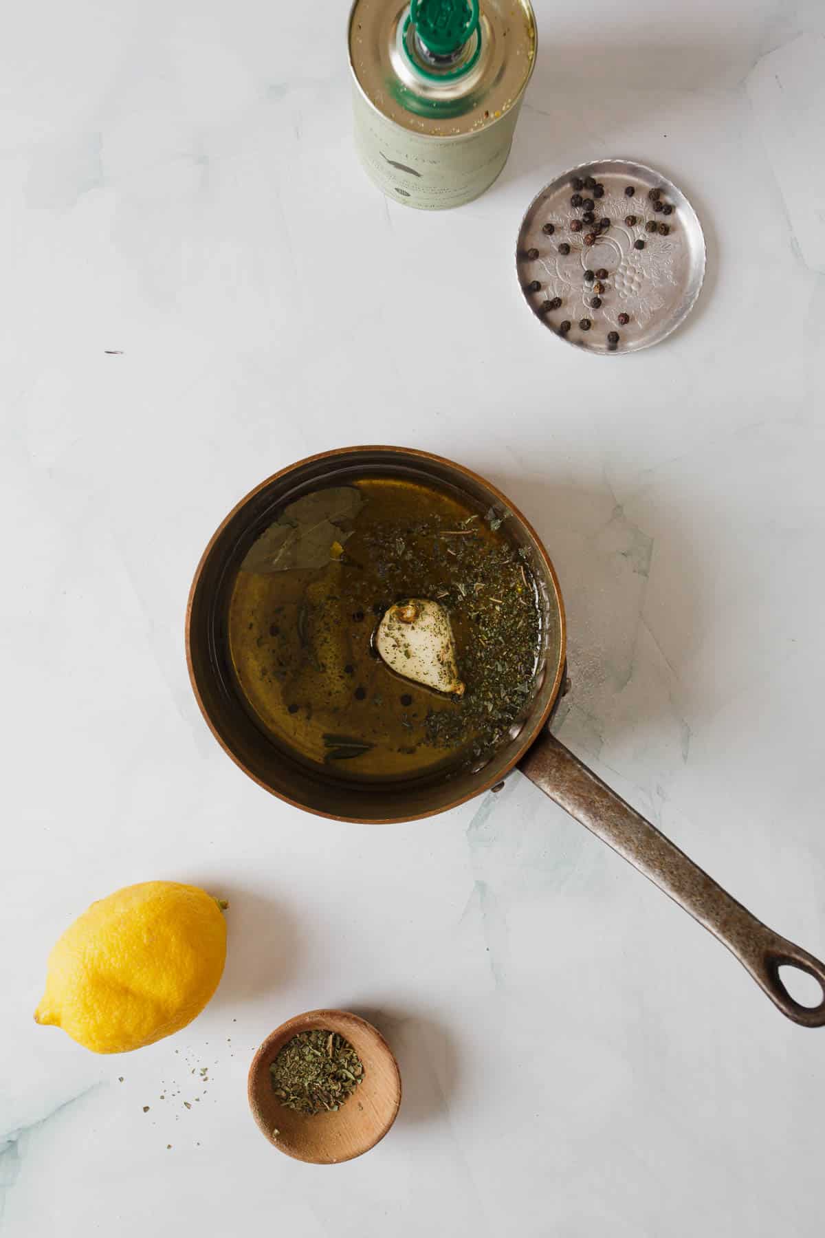 A frying pan with lemons and herbs on it.