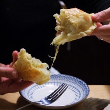 Argentinian empanada being pulled apart over a plate.