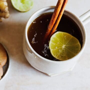 A cup of tea with cinnamon sticks and ginger.