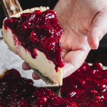 A person cutting a piece of a cranberry cheesecake that Mom makes.