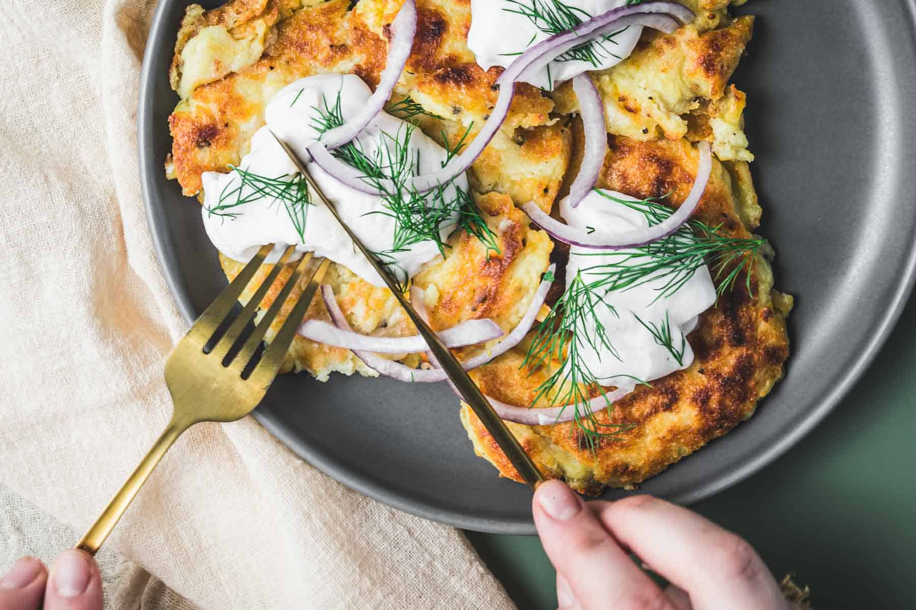 A plate of irish boxty topped with cream and herbs.