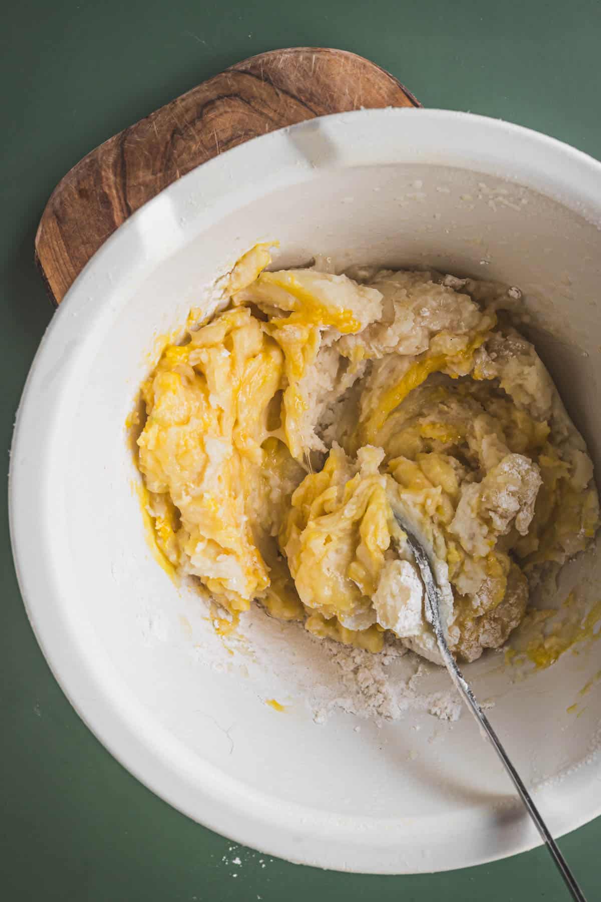 A bowl of mashed potato dough with a spoon in it.