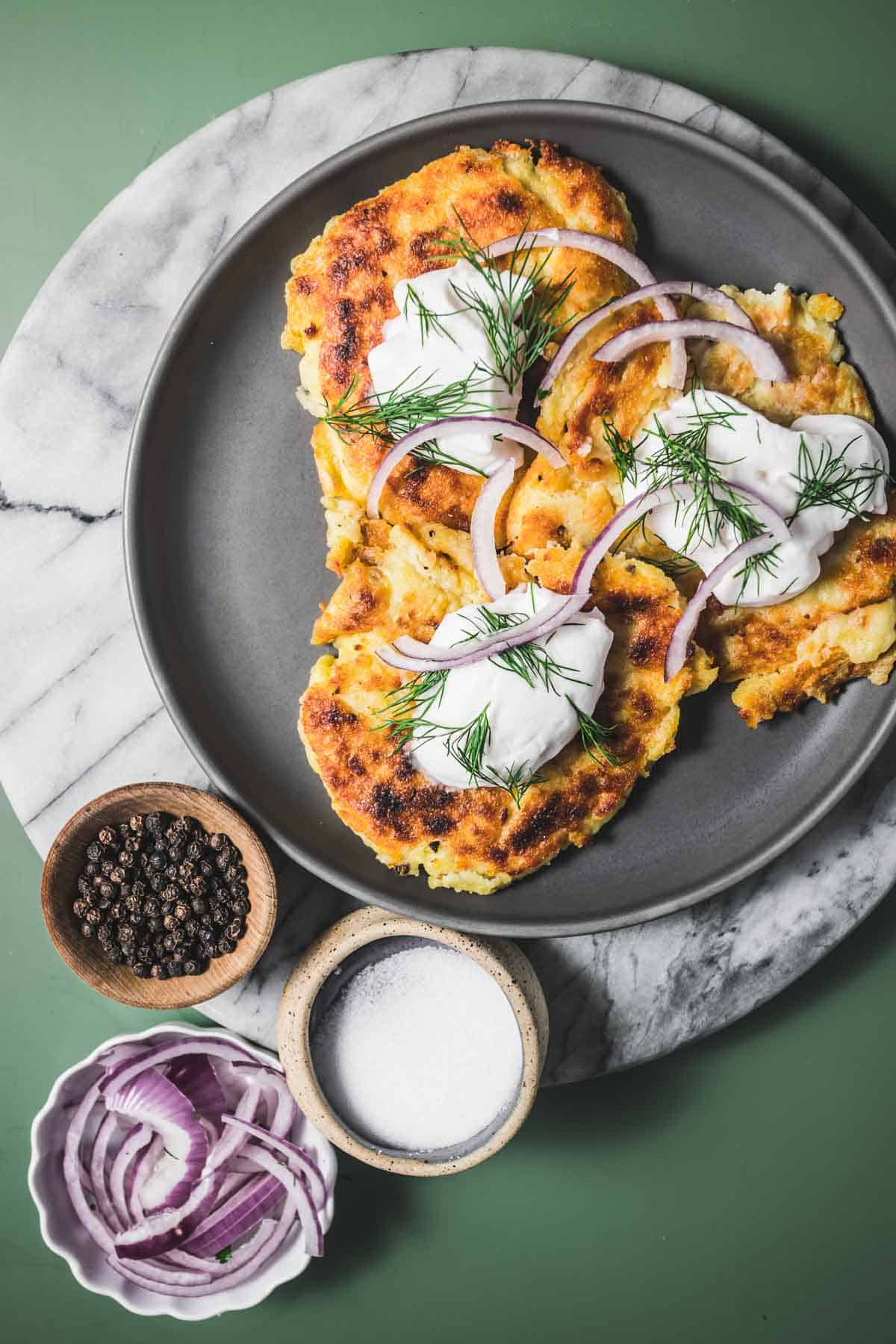 A plate of irish boxty pancakes with onions and sour cream.