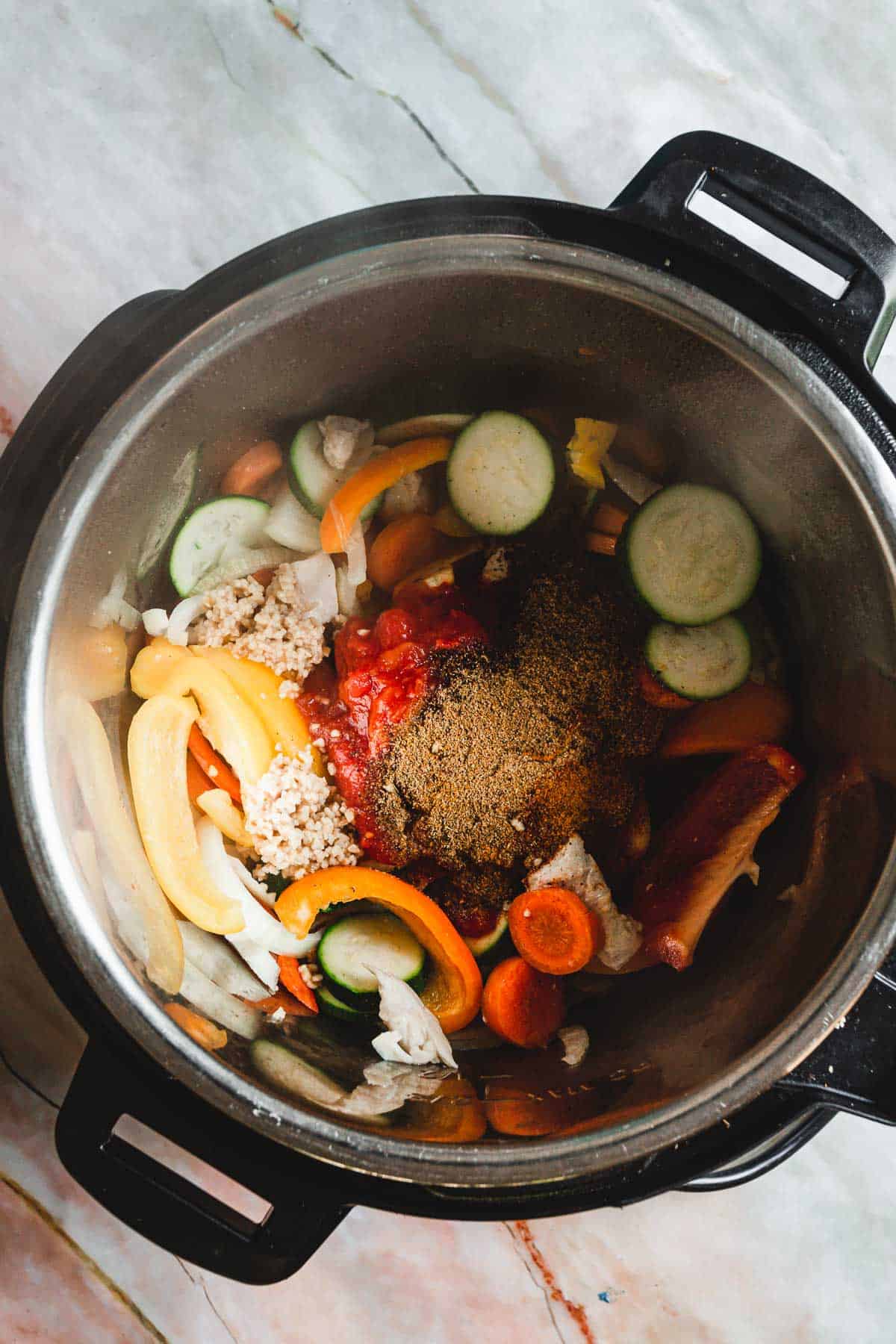 An instant pot filled with vegetables,chicken, and spices.