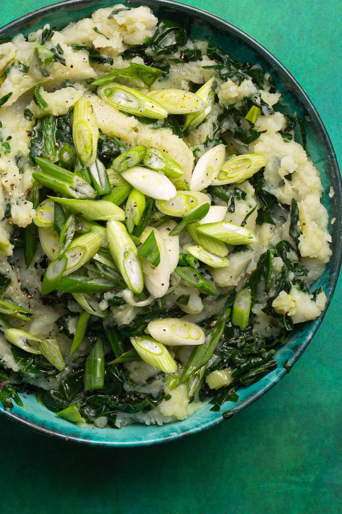 A bowl of greens and potatoes mixed together.