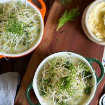 Two bowls of soup on a wooden cutting board.