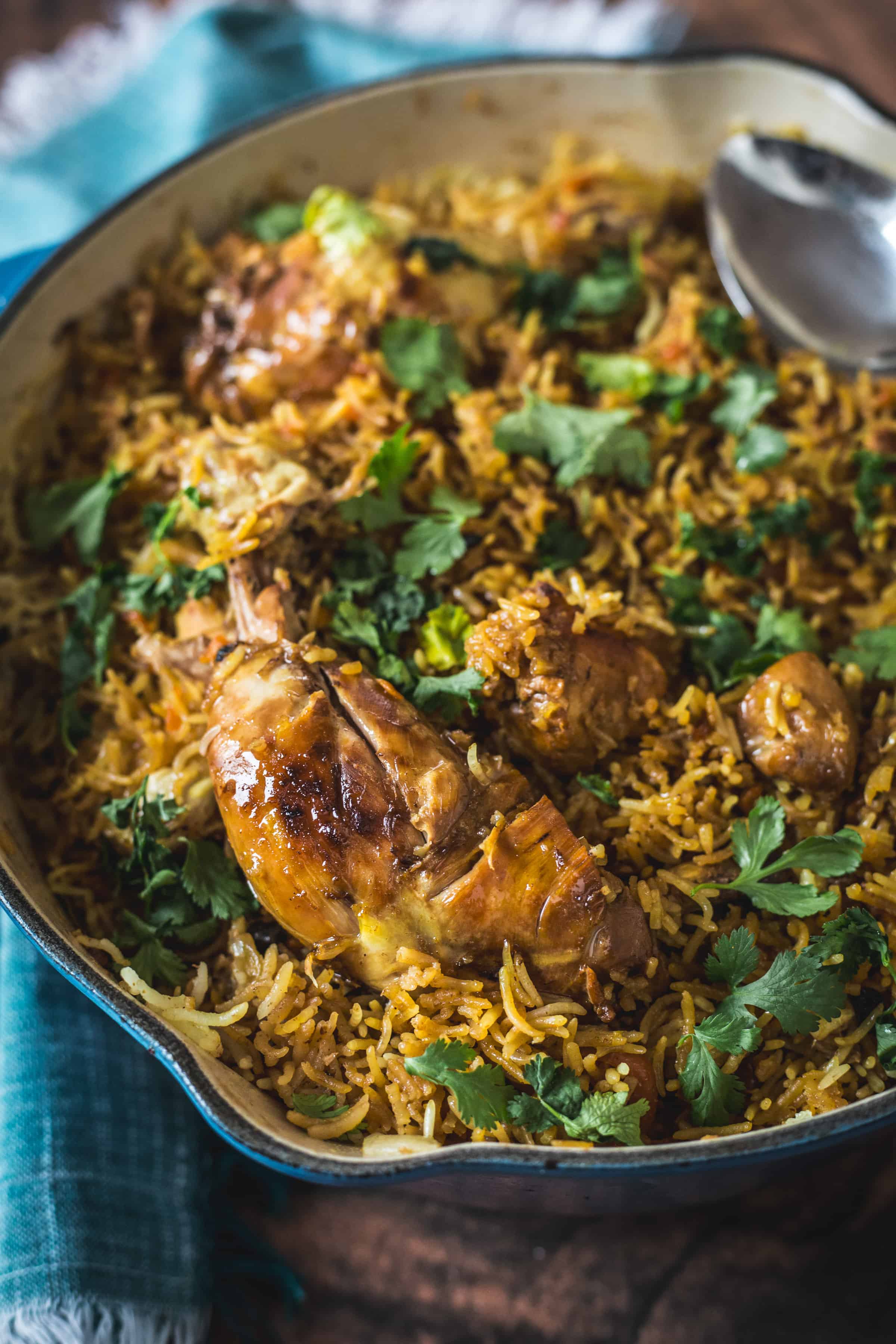 Chicken plov in a pan with a spoon.