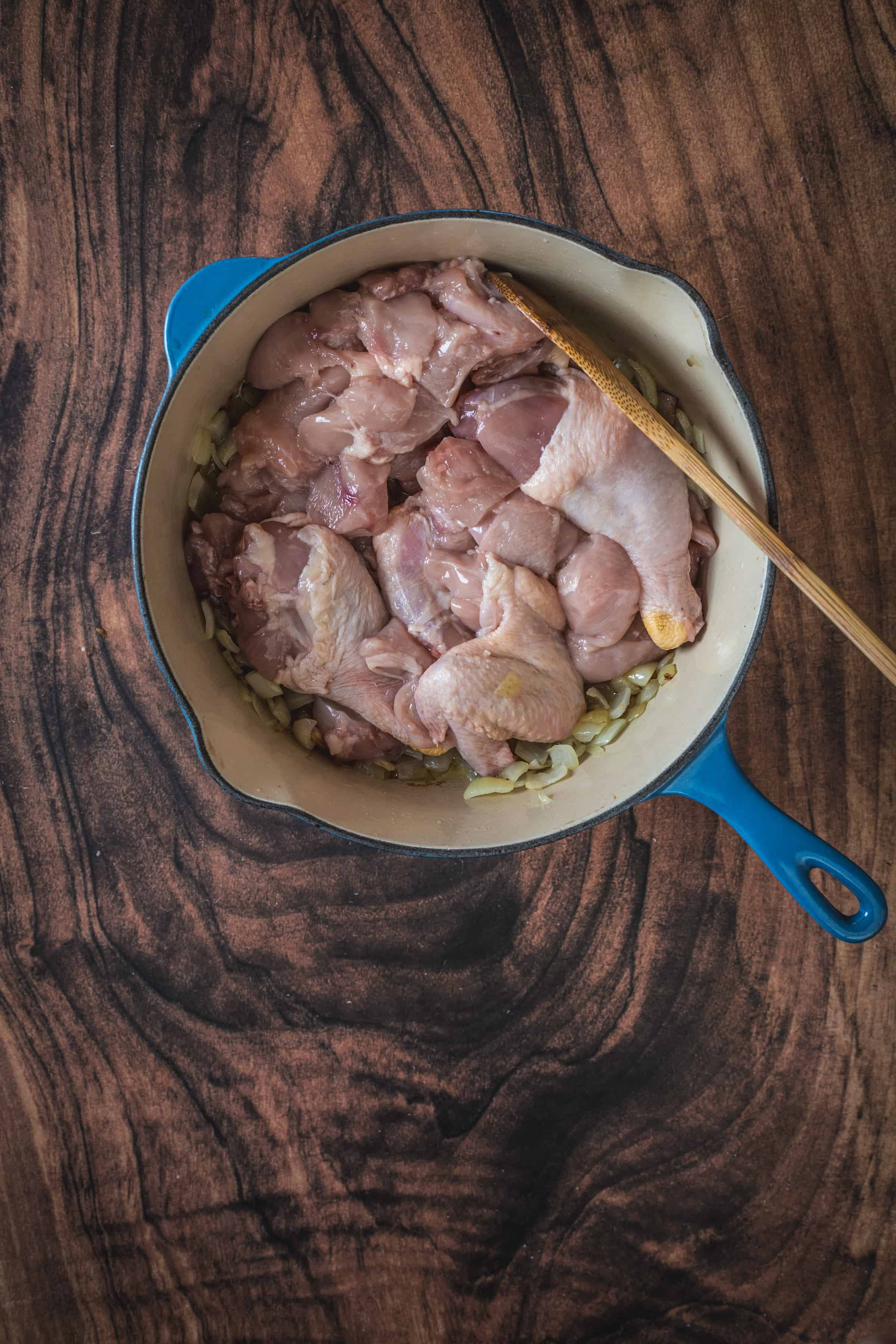 Chicken in a blue pan on a wooden table.