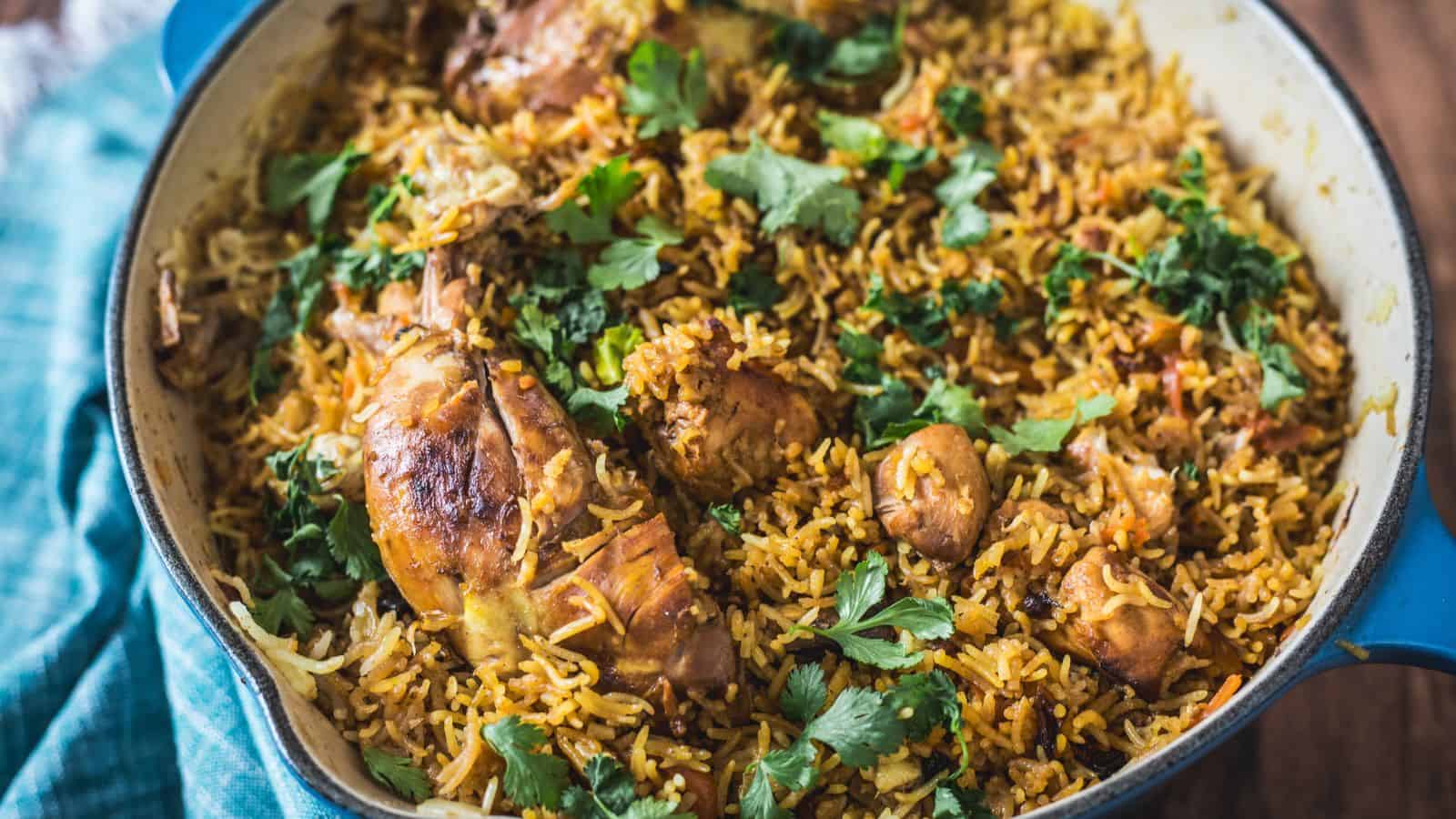 A pot filled with Grandma's recipe chicken biryani, garnished with fresh cilantro, served on a wooden surface.