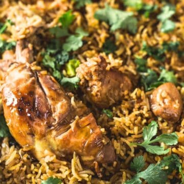 A skillet filled with biryani, a grandma's comfort food classic, featuring rice, chicken, and garnished with cilantro.