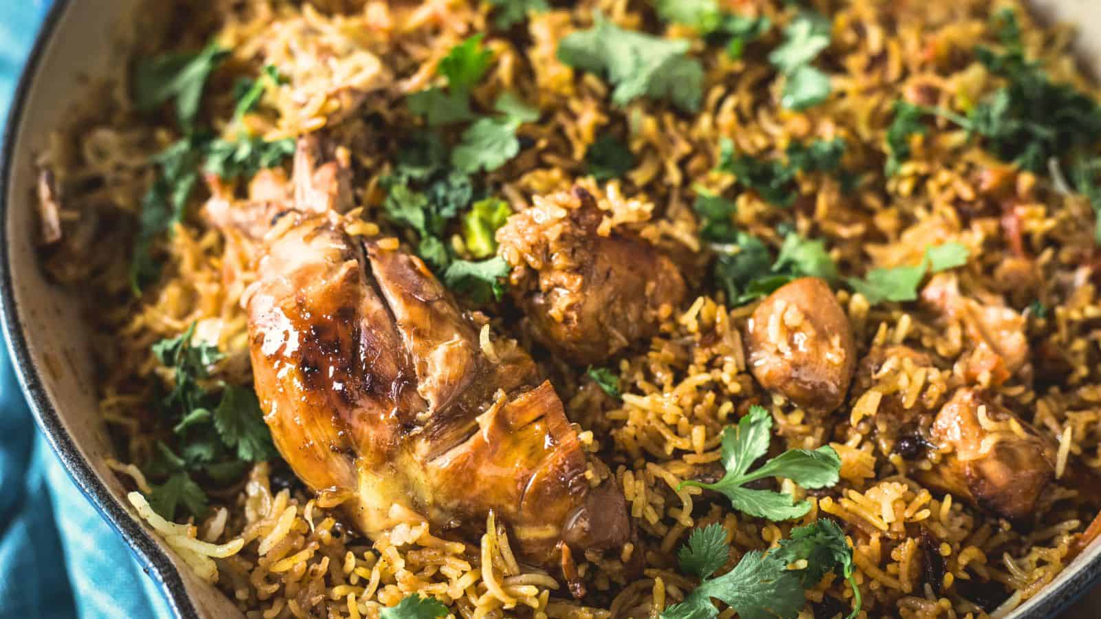 A skillet filled with biryani, a grandma's comfort food classic, featuring rice, chicken, and garnished with cilantro.