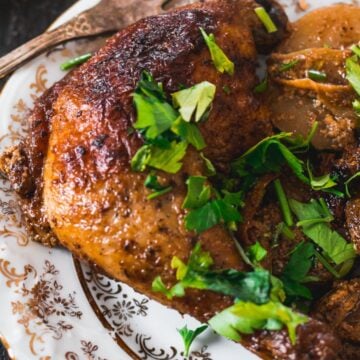 Roasted chicken with parsley and potatoes on a plate.