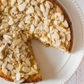 A plate of apple pie with a slice taken out of it.