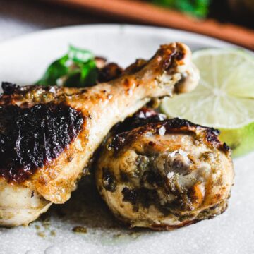 Grilled chicken drumsticks on a plate with a slice of lime, inspired by Grandma's Secret Chicken Recipes.