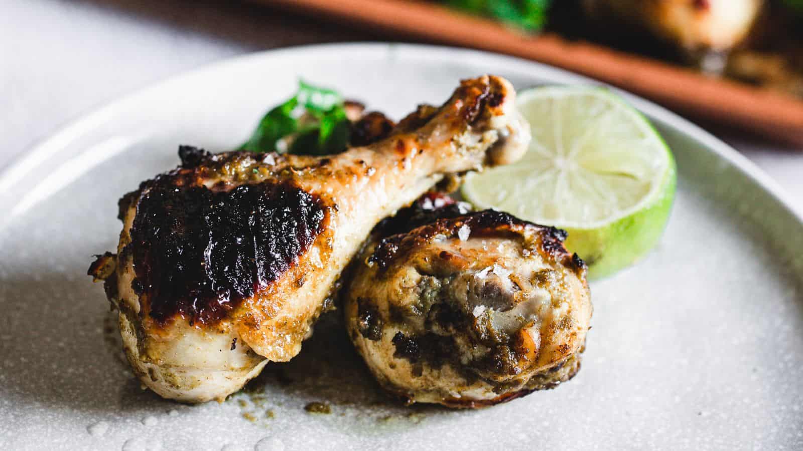 Grilled chicken drumsticks on a plate with a slice of lime, inspired by Grandma's Secret Chicken Recipes.