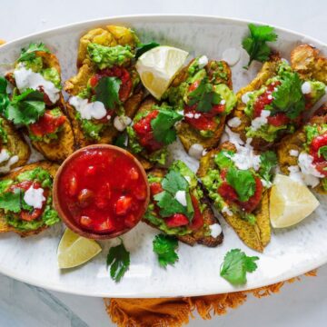 Savoury Mexican chiles rellenos with avocado, tomato, and cilantro on a white platter.