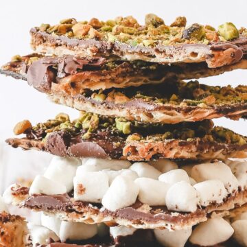 A stack of chocolate bark pieces topped with chopped pistachios and marshmallows, reminiscent of grandma's classic recipes. The layers include visible swirls of chocolate, nuts, and marshmallows, all stacked on a light-colored surface.