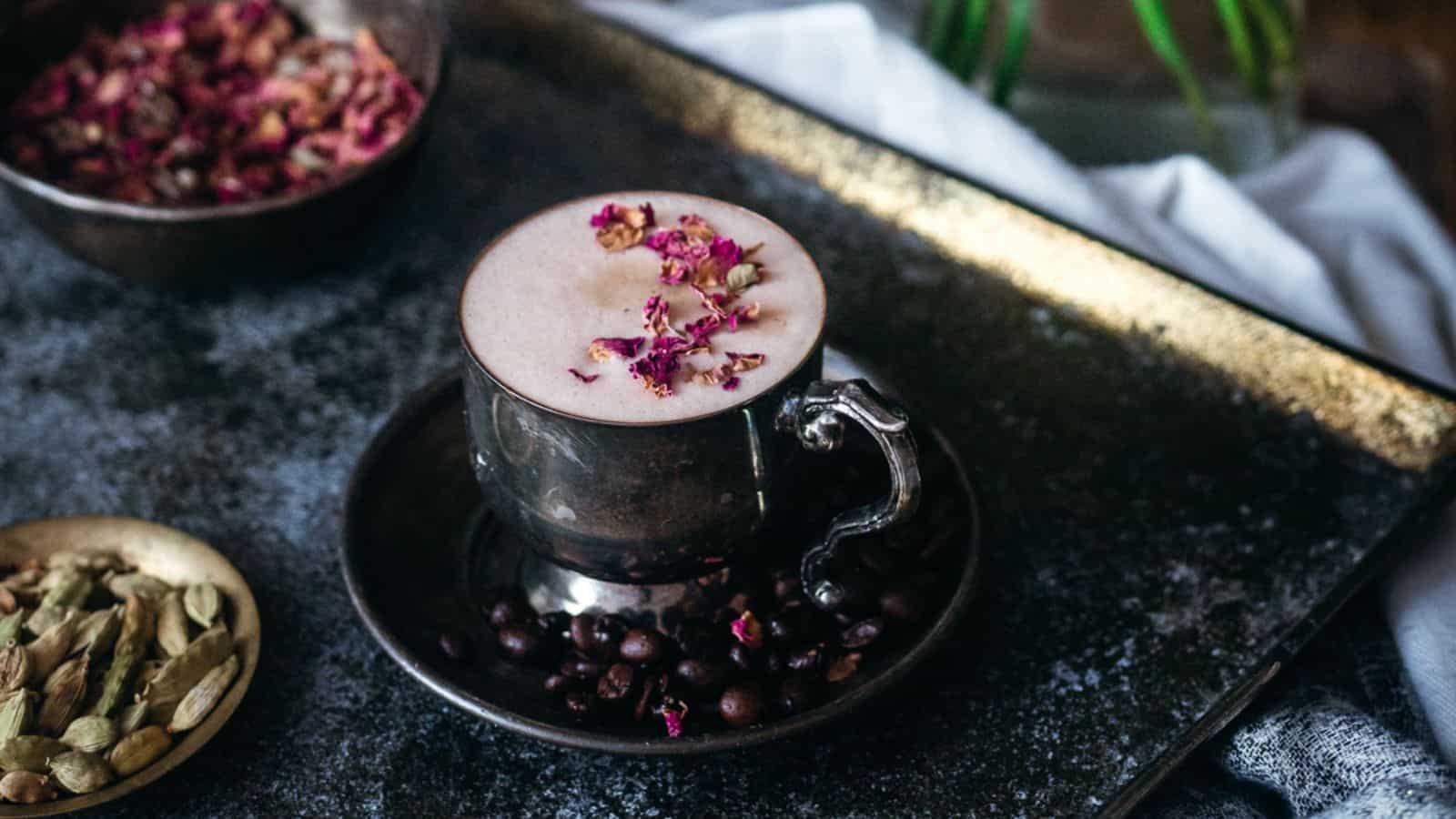 A cup of coffee with rose petals and pistachios.