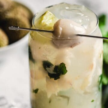 Try a refreshing cocktail with mint leaves and a lychee garnish, served on ice in a tall glass.