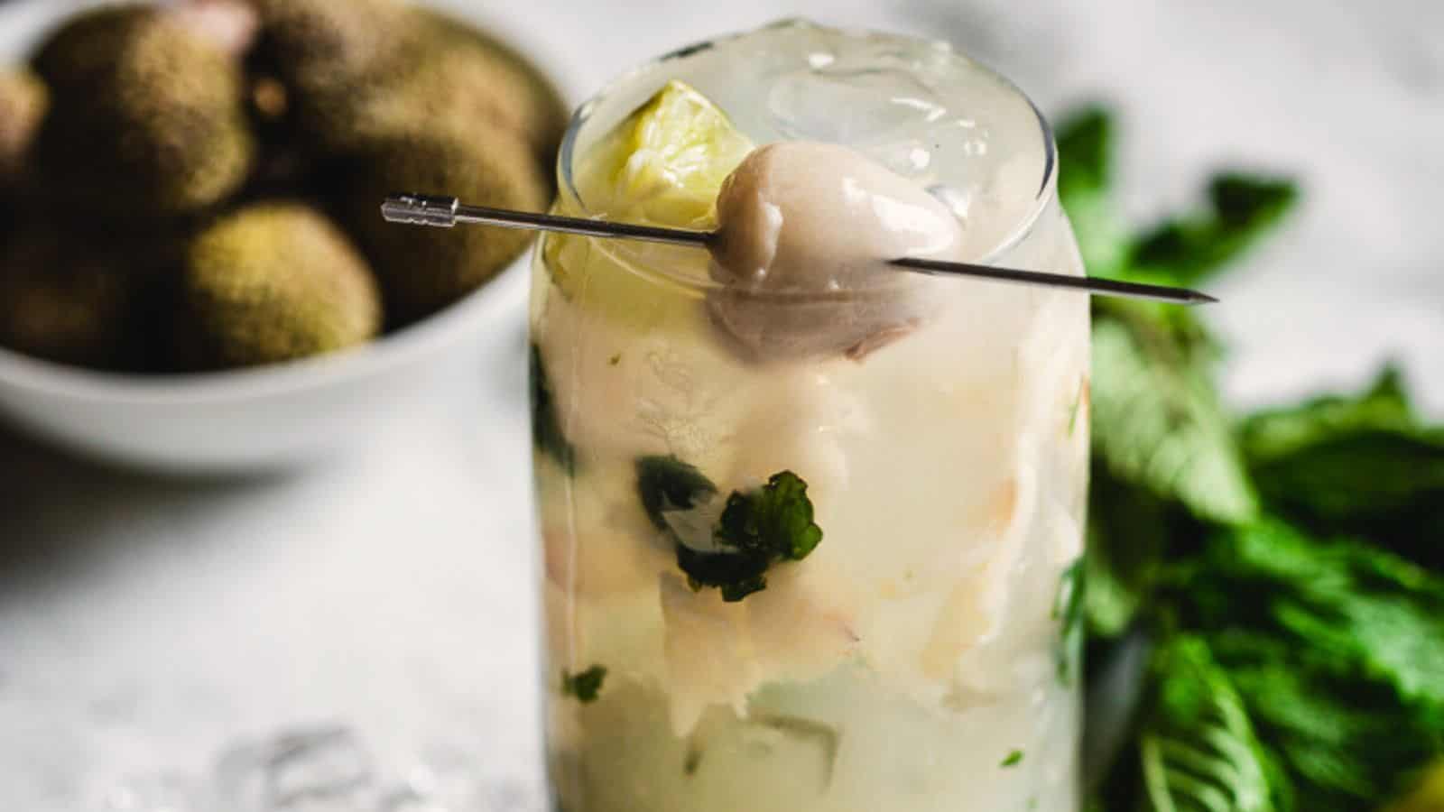 Try a refreshing cocktail with mint leaves and a lychee garnish, served on ice in a tall glass.