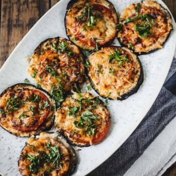 A plate of baked eggplant slices topped with melted cheese and garnished with herbs, ready to serve for dinner in just 30 minutes.