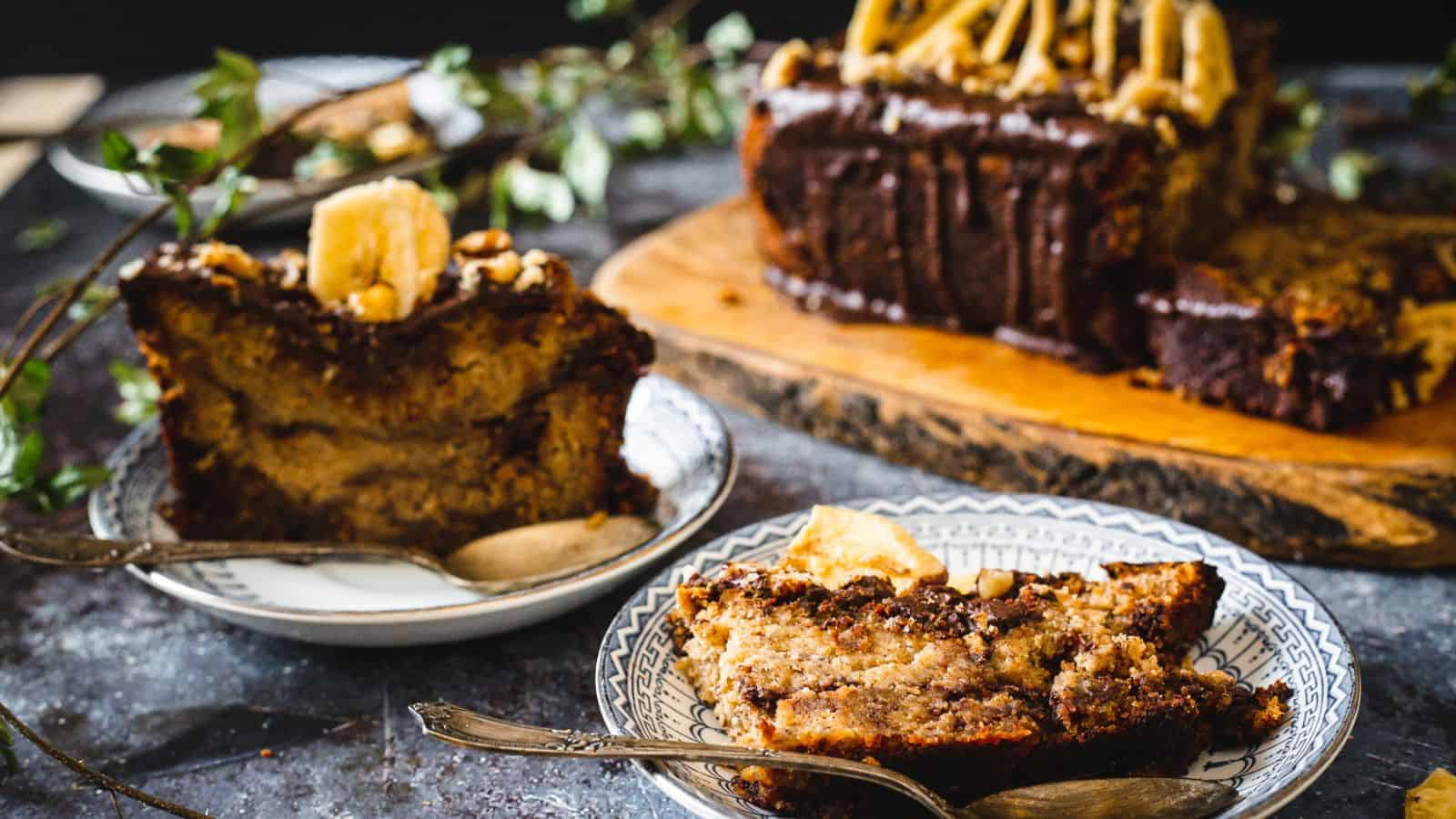 Two slices of chocolate banana bread with loaf in background.