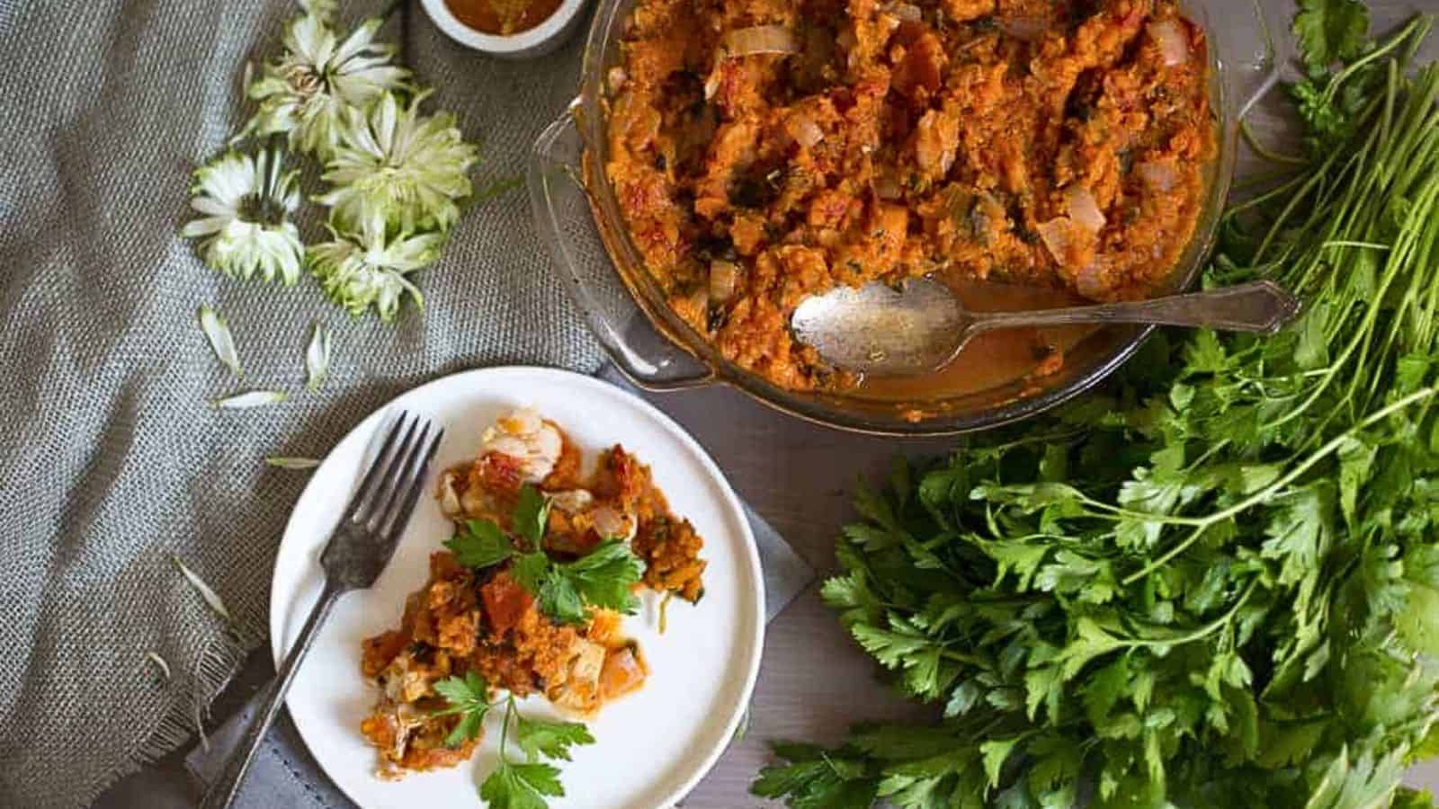 A plate of food on a table next to a bowl of parsley.