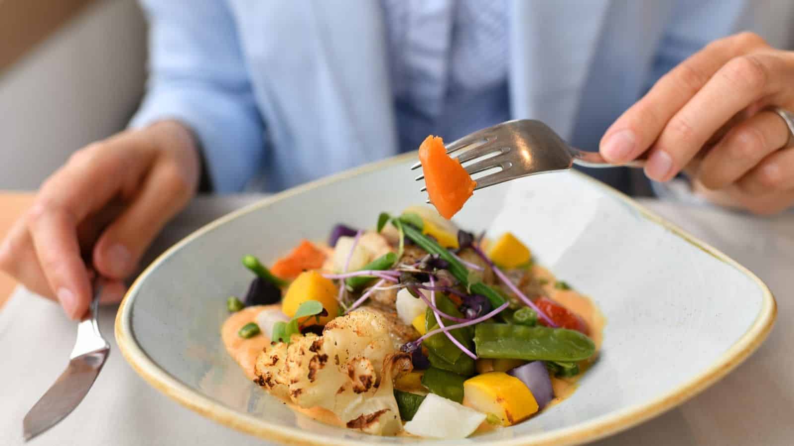 A person eating veggies from a bowl.