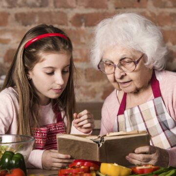 Grandma reading a book with a girl.