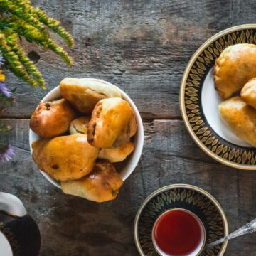 Two plates with piroshki on them alongside tea.