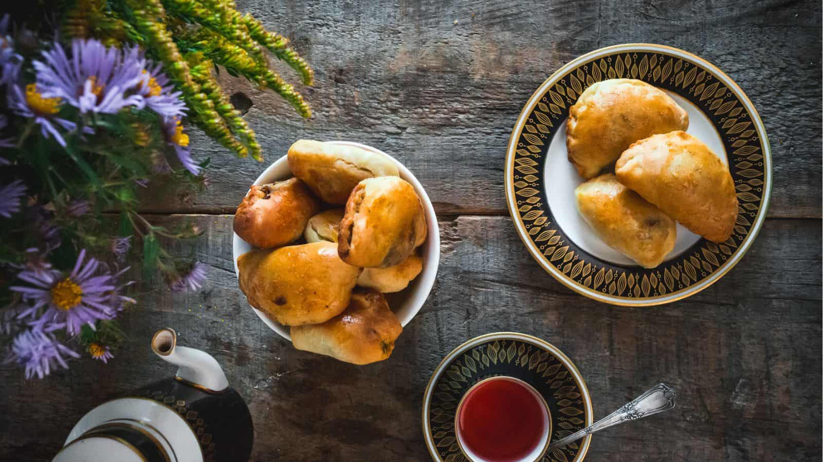 Three piroshki on a plate with tea.