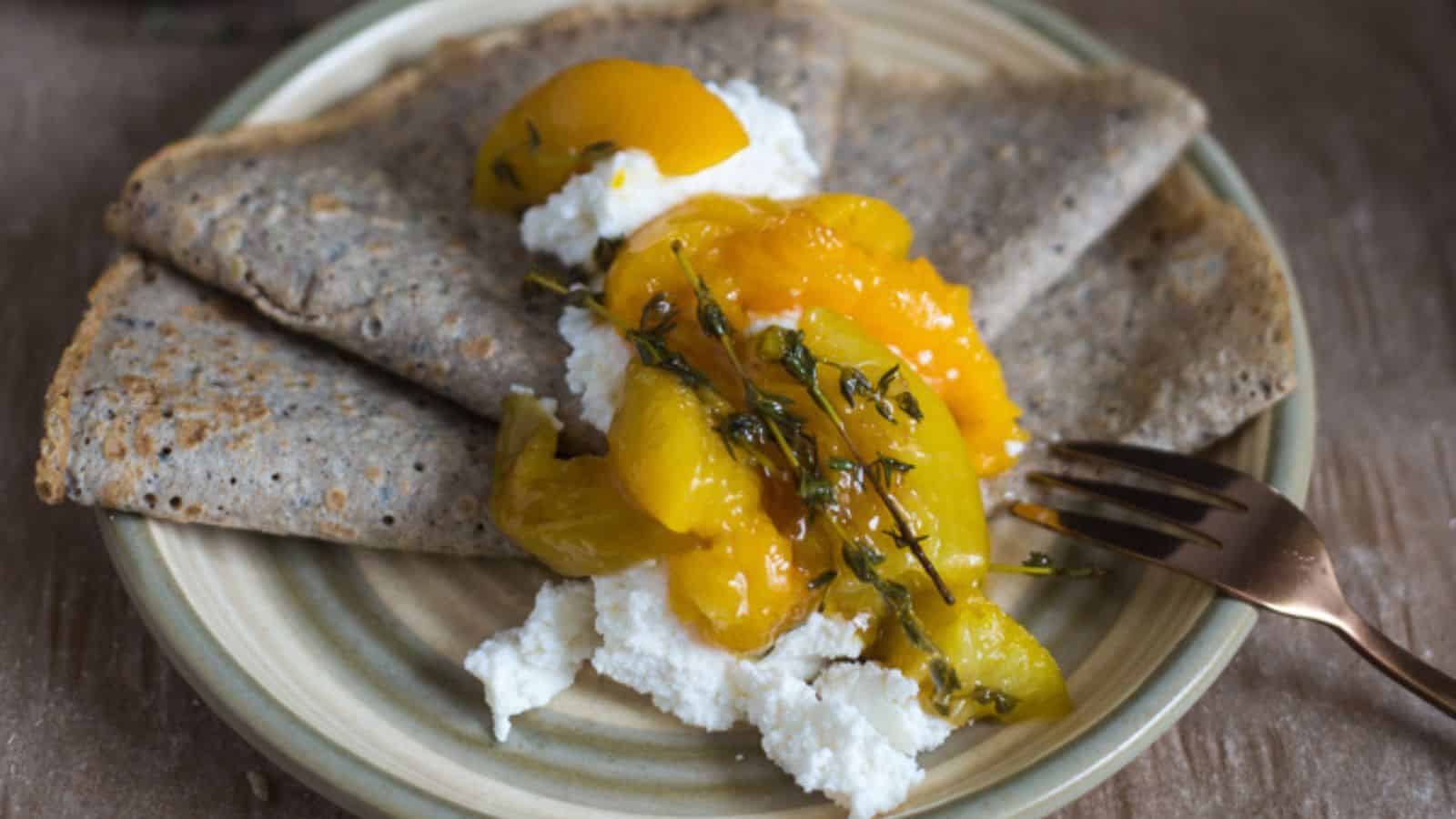 One crepe folded on a plate with ricotta and pancakes.