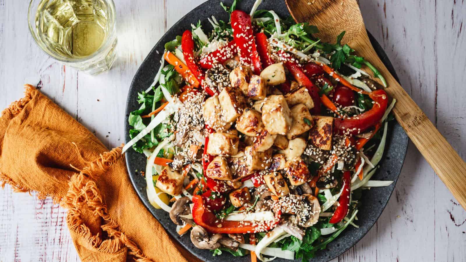 Large plate of fried halloumi salad with wine glass.