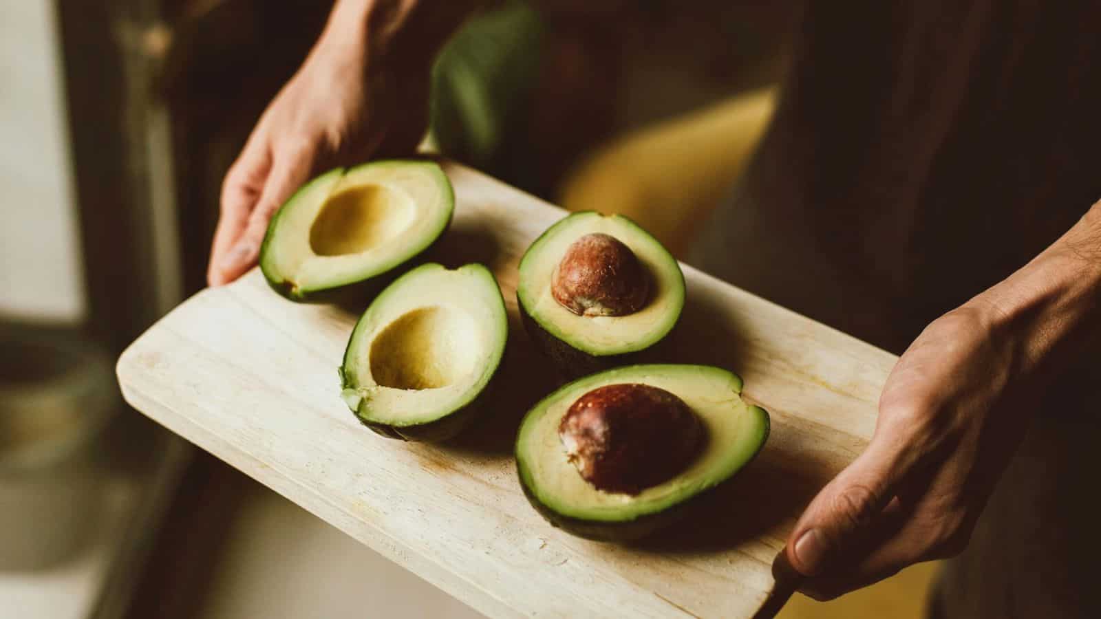 Person holding a tray of sliced avocados