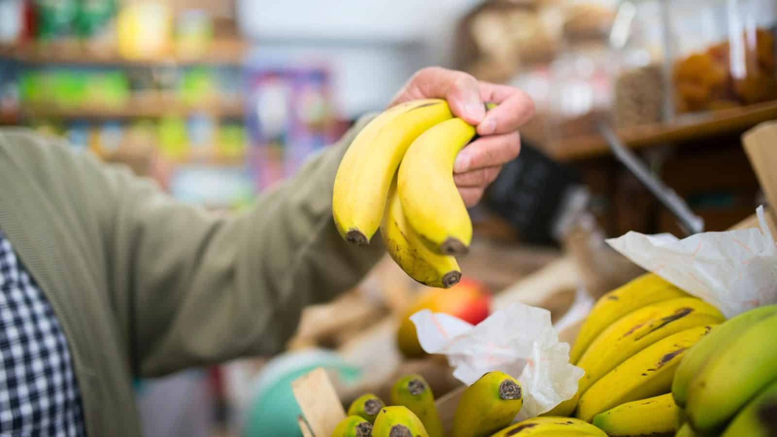 Person holding three bananas in a grocery store