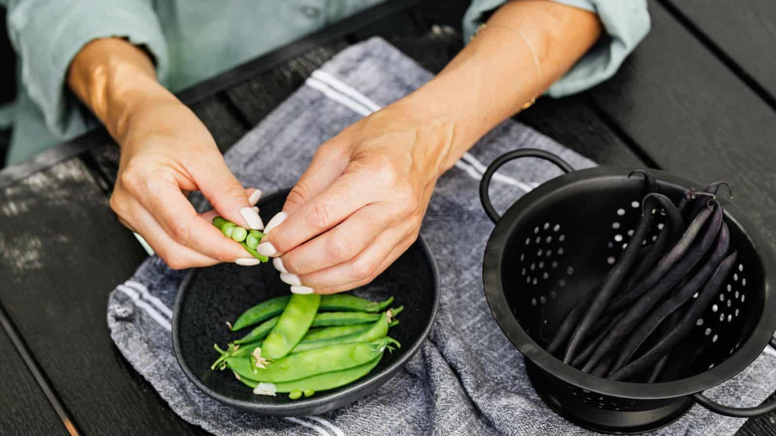 Person holding beans on top of a pan