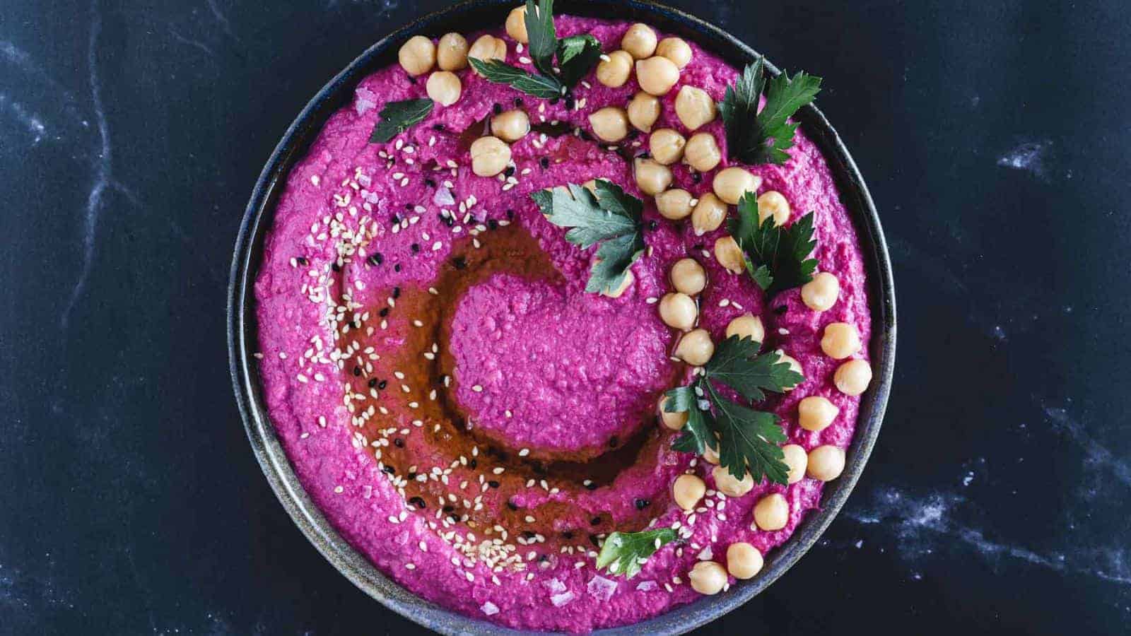 Overhead view of beet hummus with chickpeas and sesame seeds.