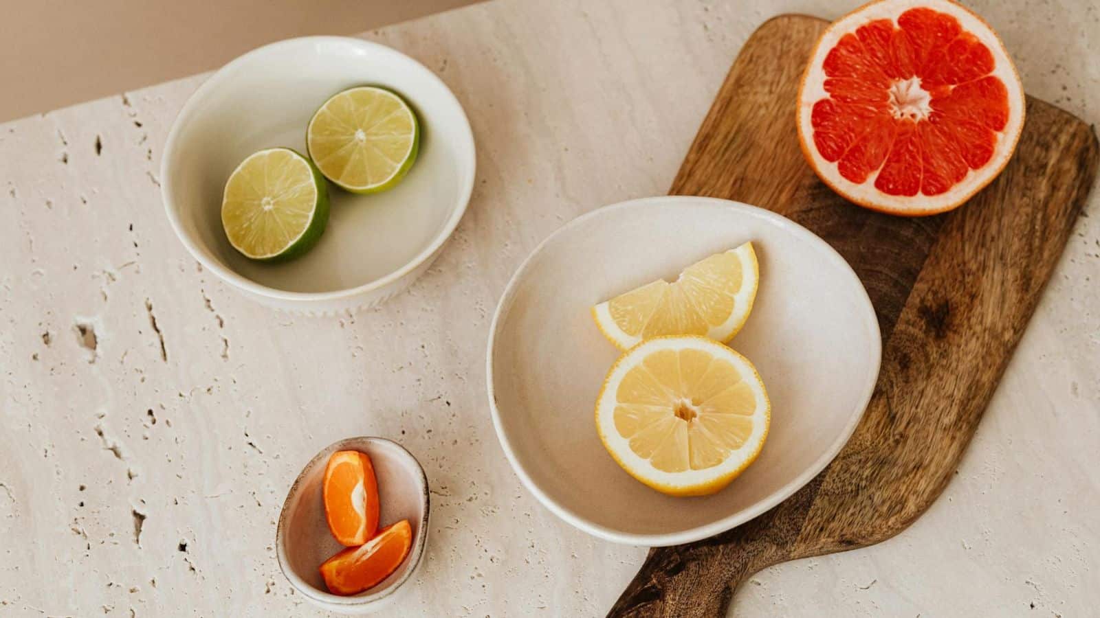 An assortment of citrus fraits placed on bowls and on a chopping board