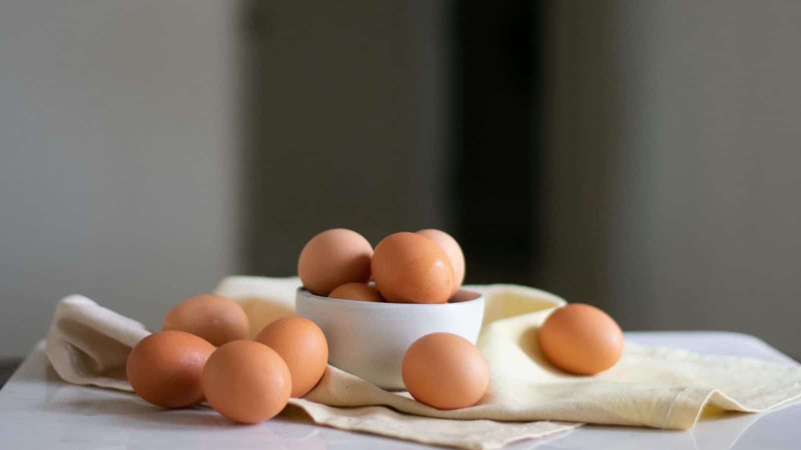 Eggs in a bowl and on a piece of tablecloth