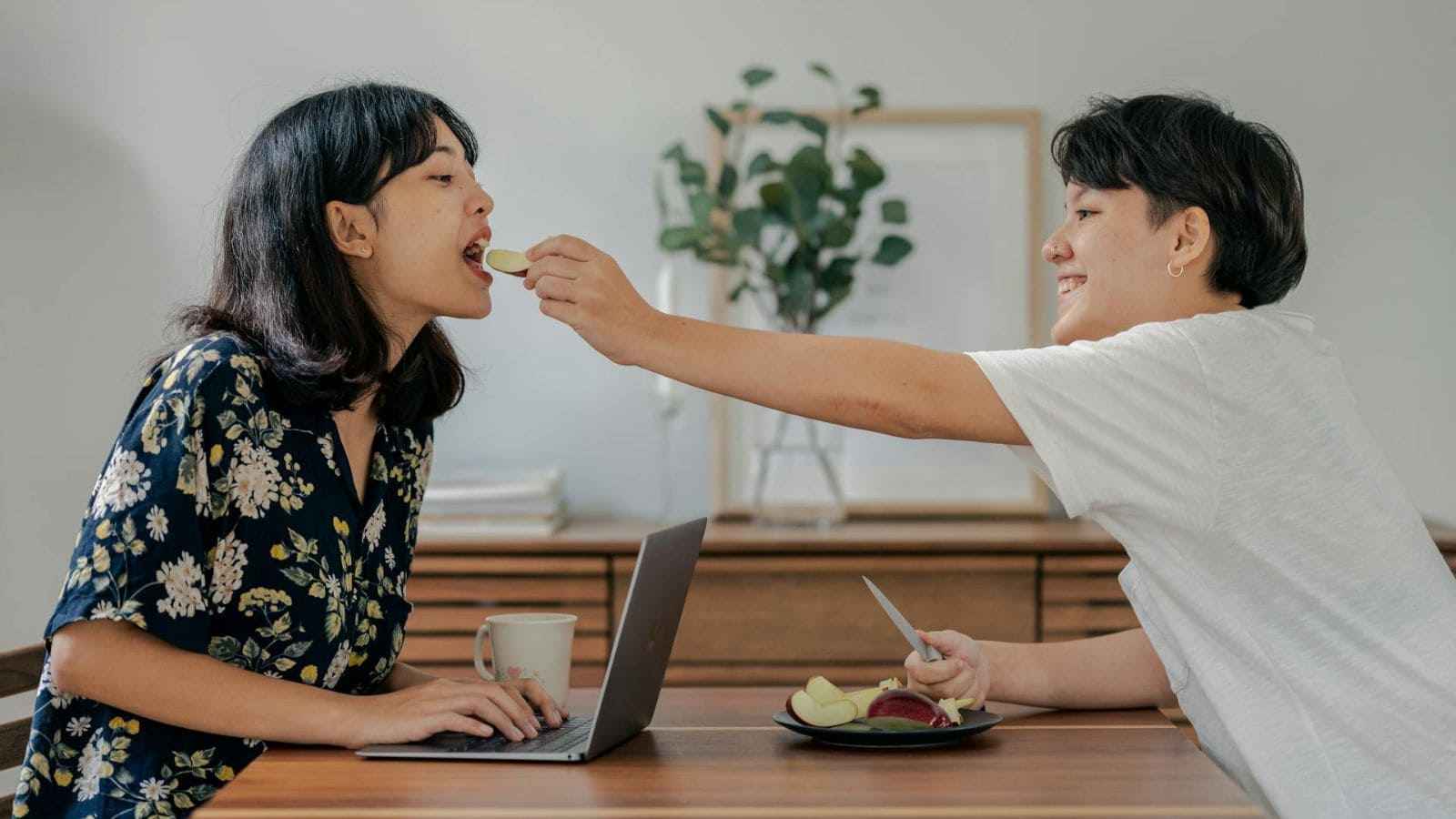 A person feeds another person sliced apples