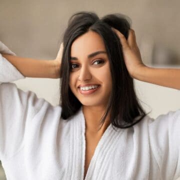 Woman in bath robe holding hair with both hands