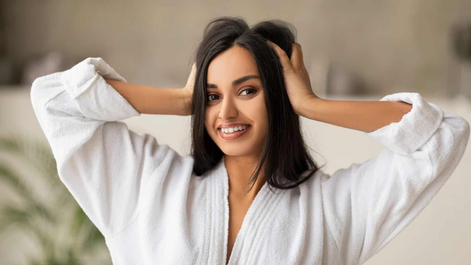 Woman in bath robe holding hair with both hands